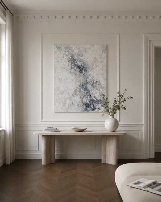 Modern interior with abstract painting, marble table, and vase on a wall.