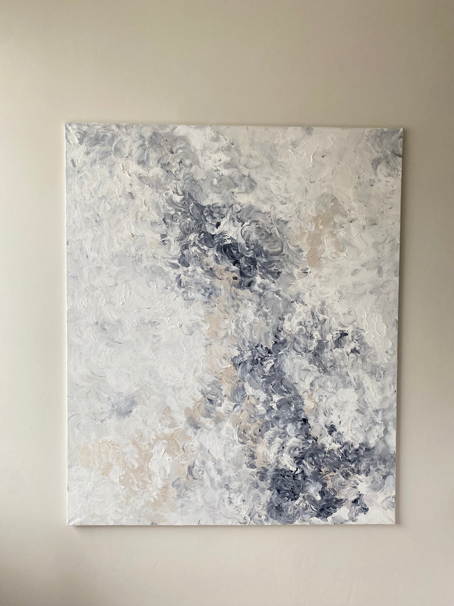 Abstract art painting with gray, blue, and beige tones on a beige wall.