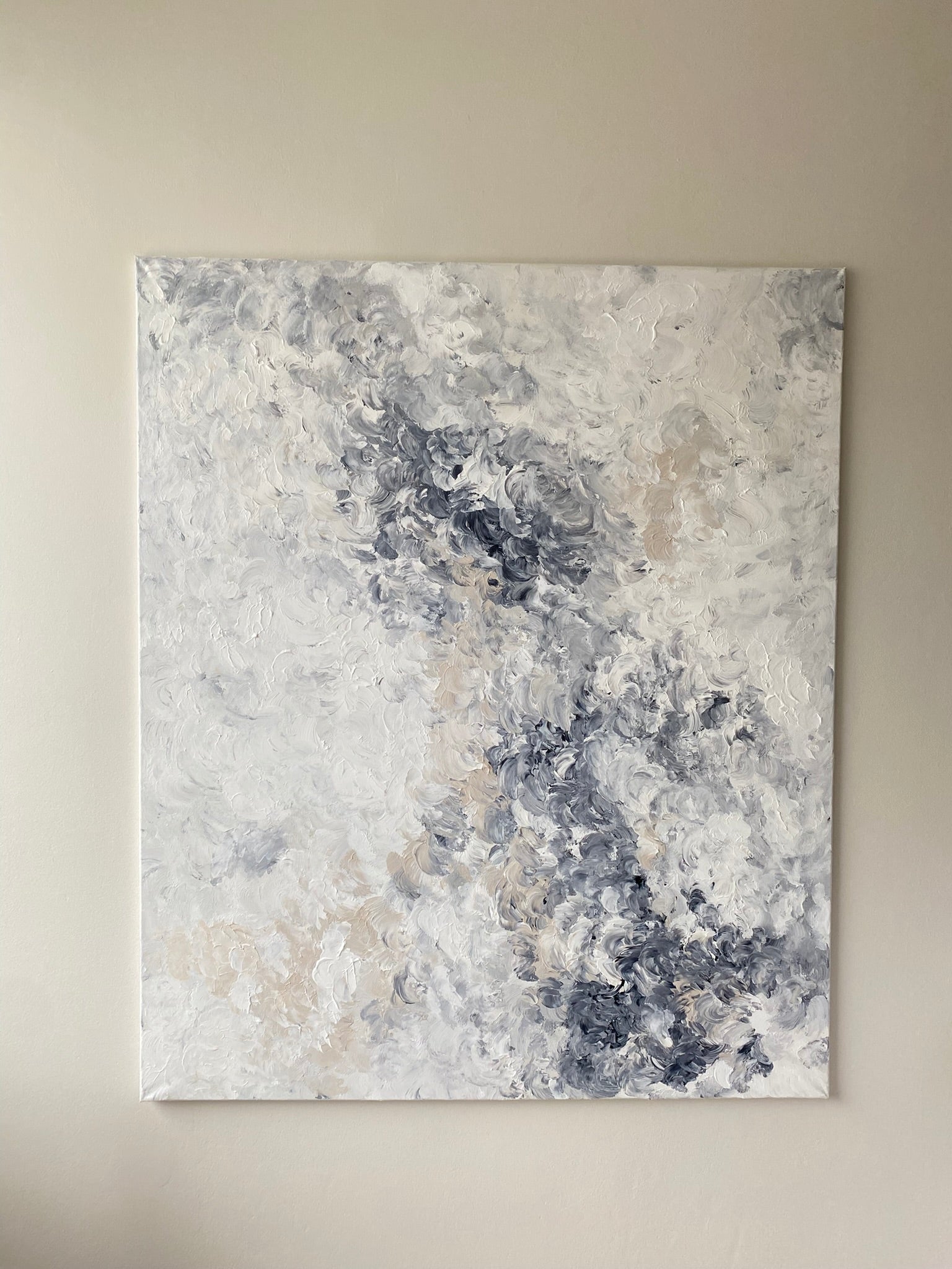 Abstract art painting with gray, blue, and beige tones on a beige wall.