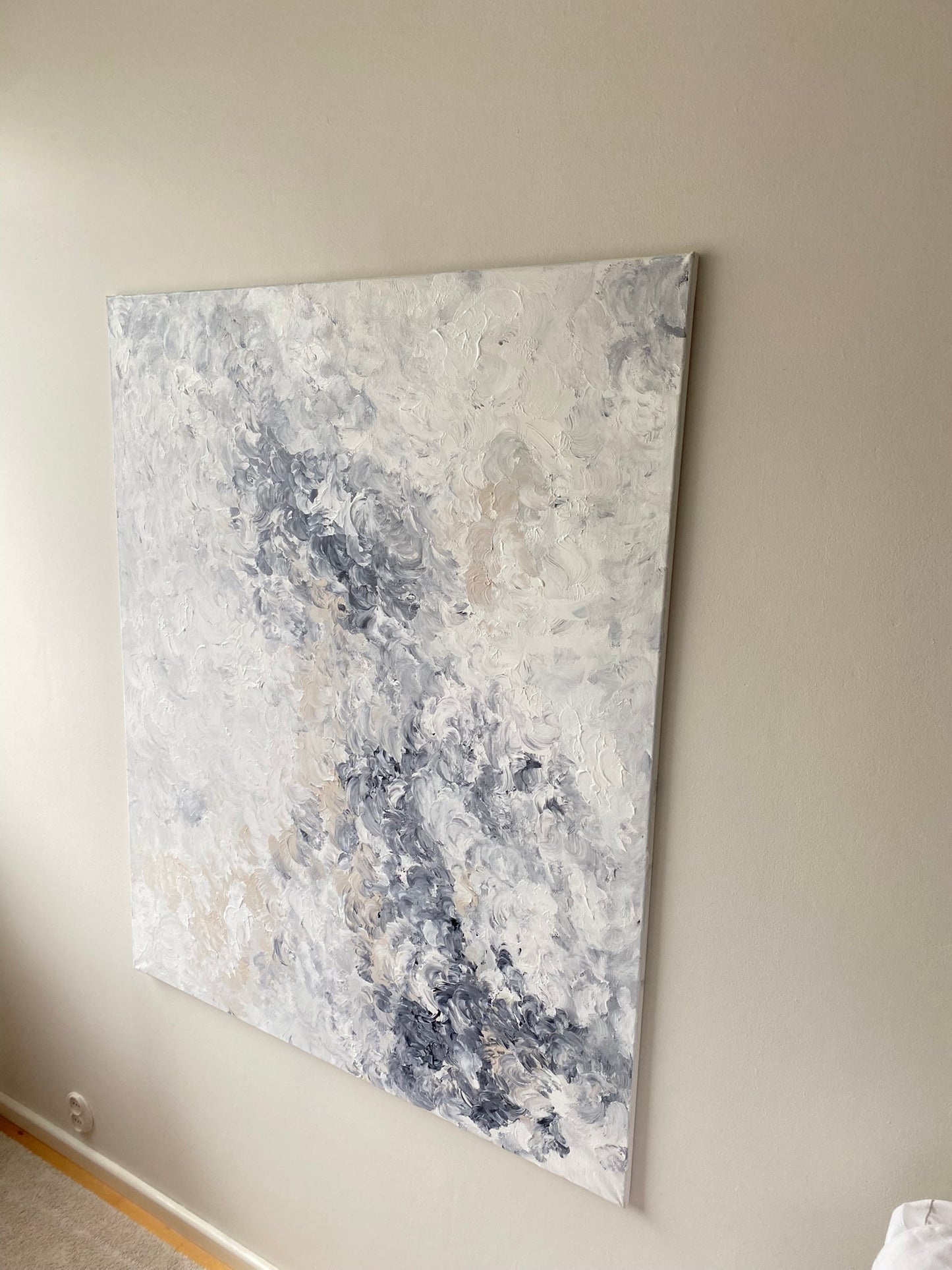 Abstract painting with gray and white tones on a beige wall