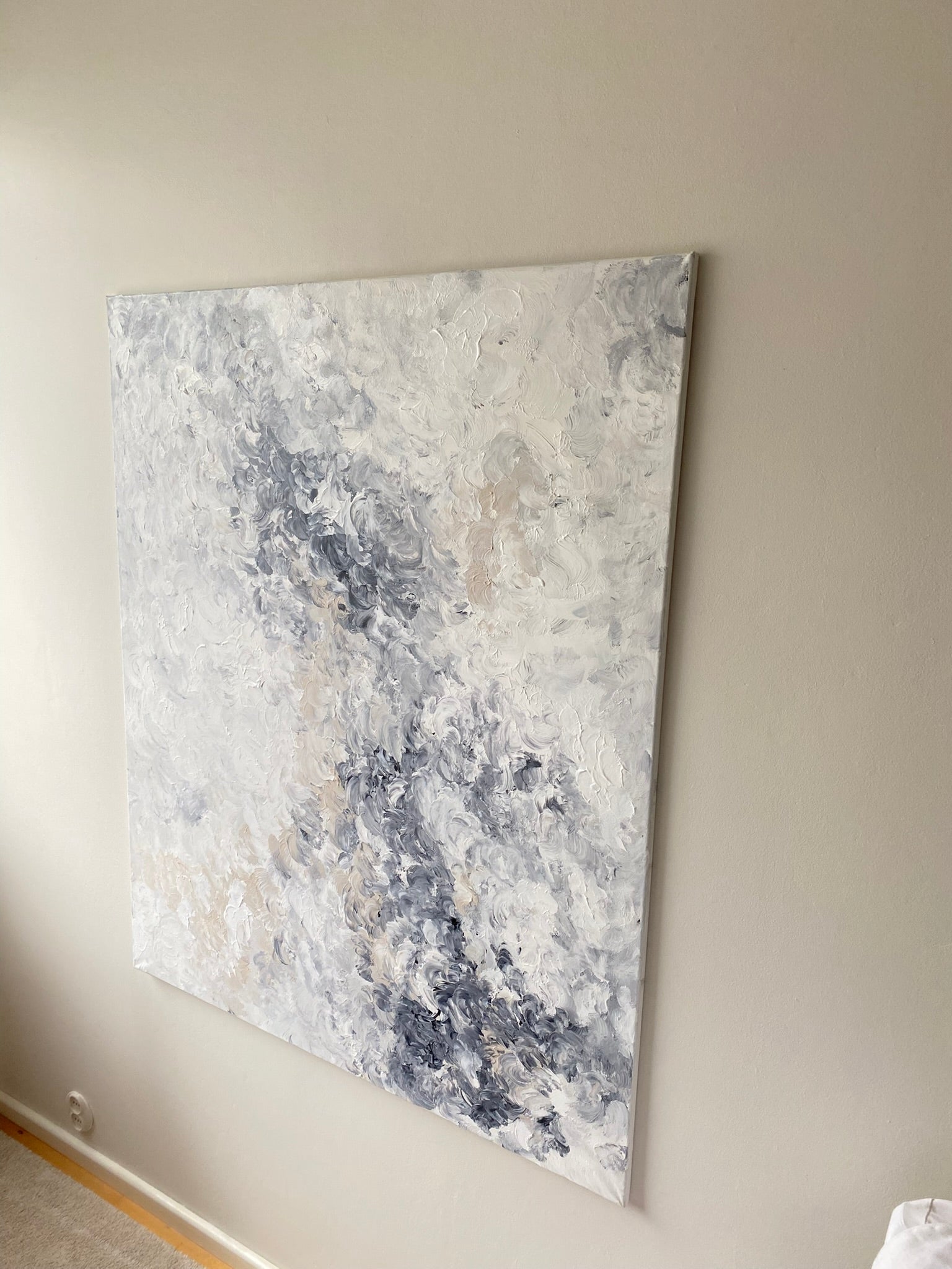 Abstract painting with gray and white tones on a beige wall