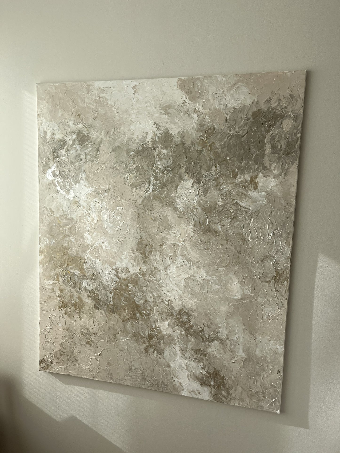 Textured beige wall art on a plain wall